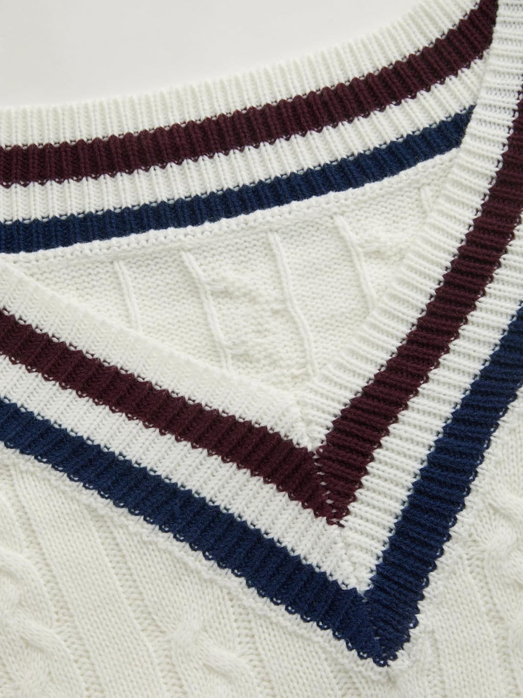 Close-up of cream V-neck knit sweater with navy and wine striped rib trim