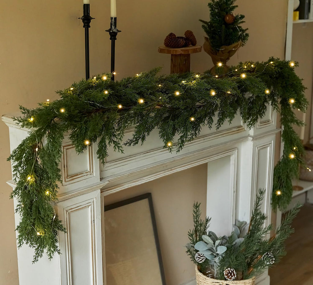 Artificial Christmas garland with warm LED string lights wrapped along a fireplace mantel edge