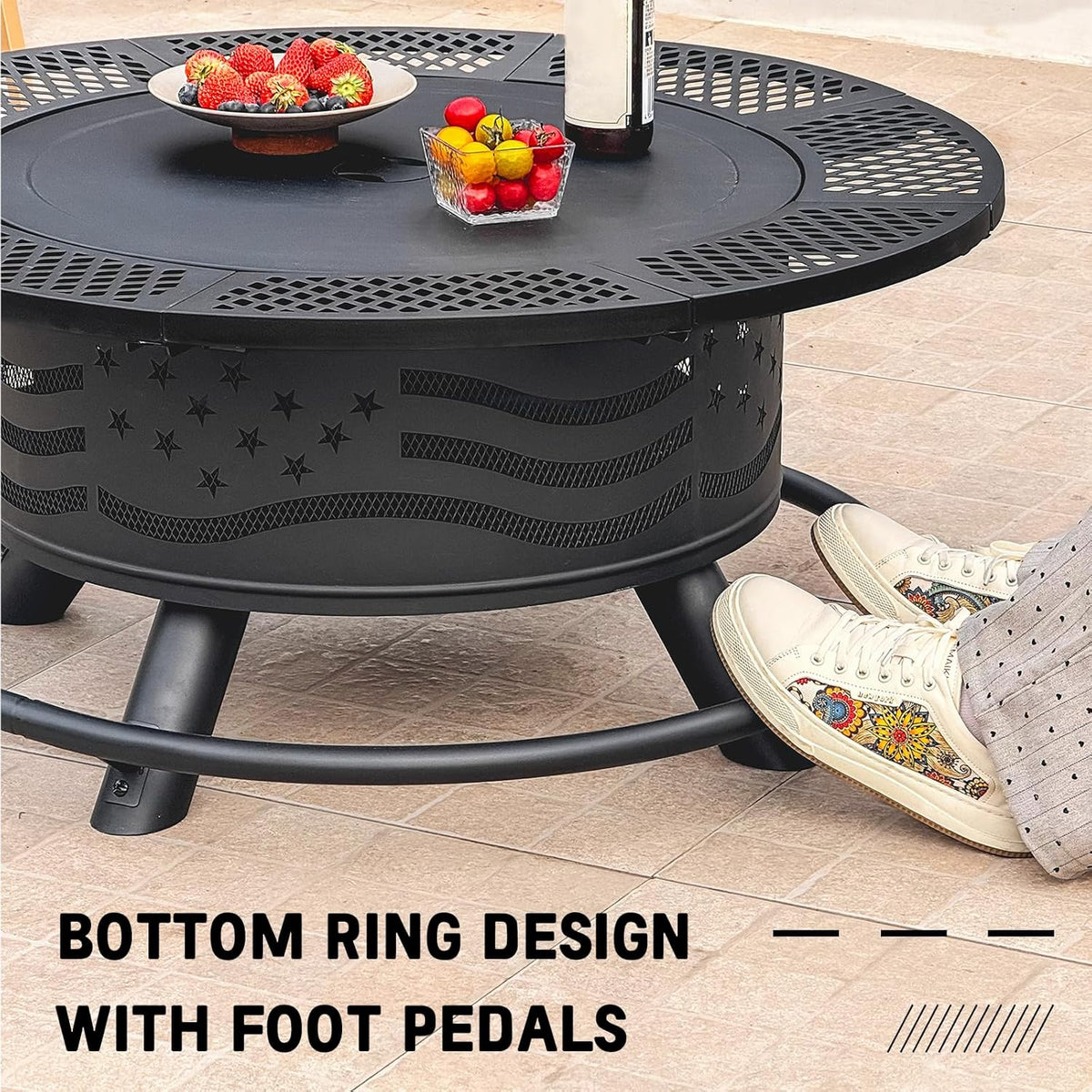 Black round fire pit with bottom ring and foot pedals, shown beside sneakers