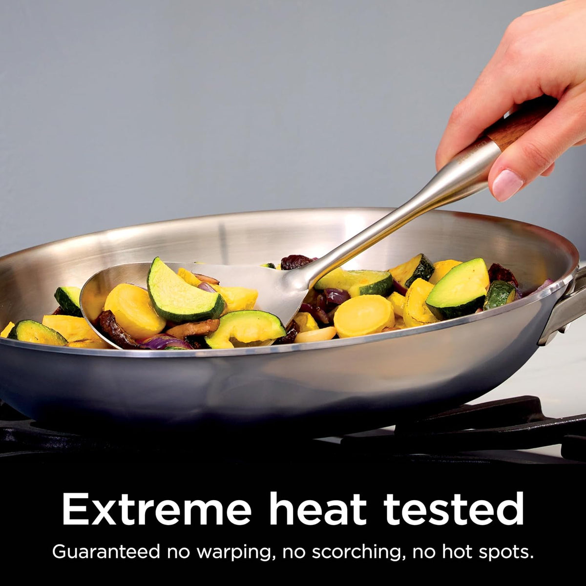 Ninja EverClad stainless steel fry pan with vegetables and a metal spatula