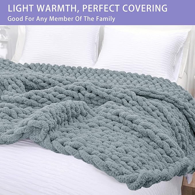 Dusty blue chunky knit throw blanket draped over a bed with textured stitch pattern