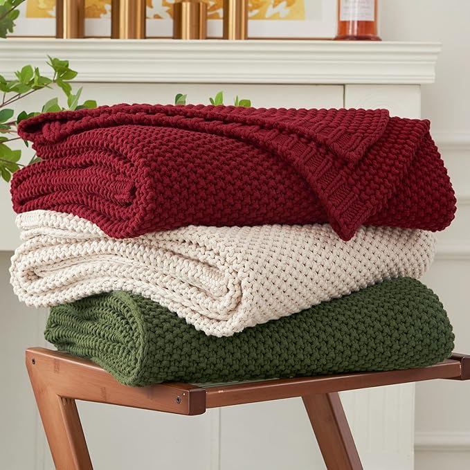 Burgundy chunky cable-knit throw blanket, folded on a wooden bench