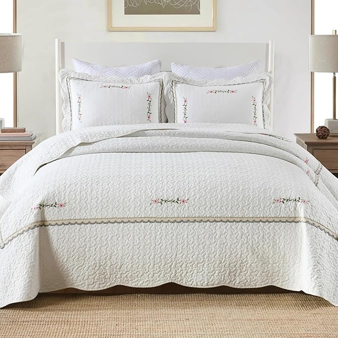 White cotton quilt coverlet with stitched floral embroidery and striped trim
