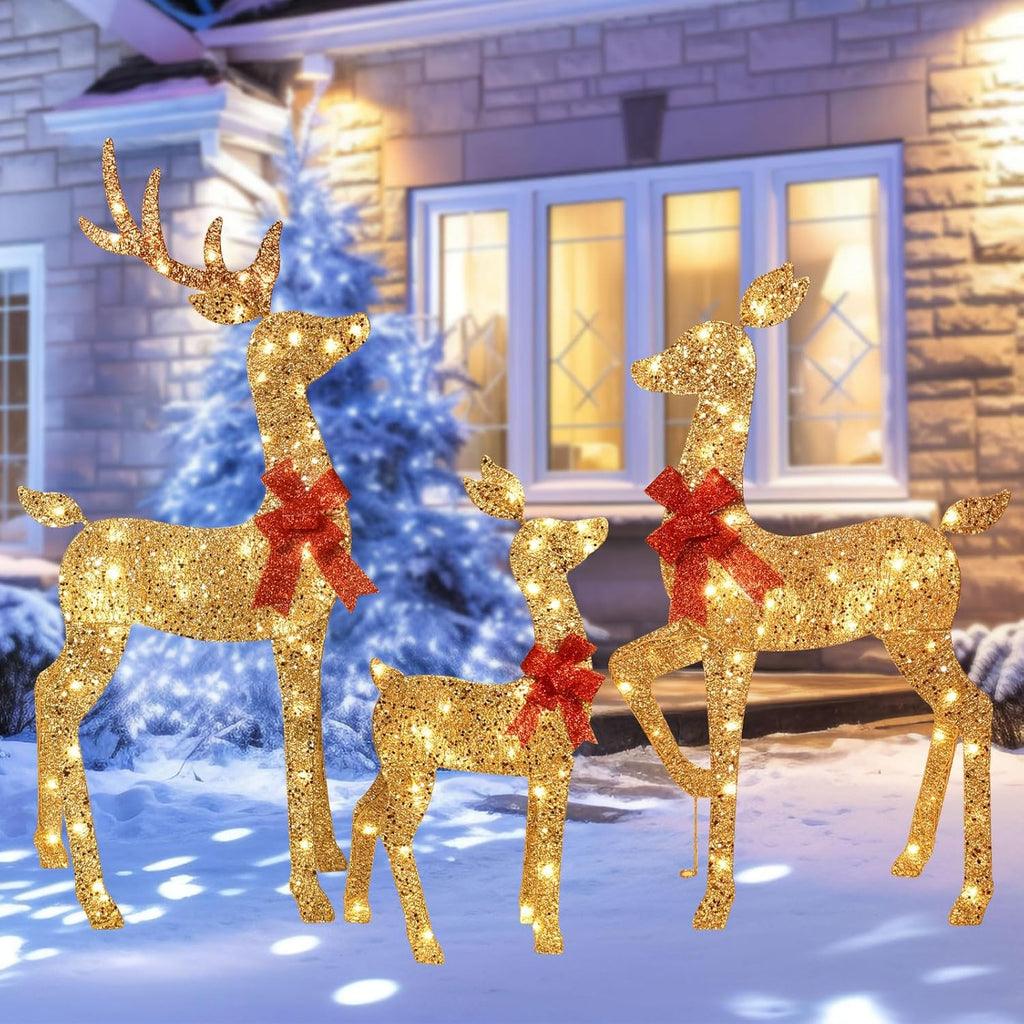 Glowing gold glitter deer family decoration with red bows on snowy walkway
