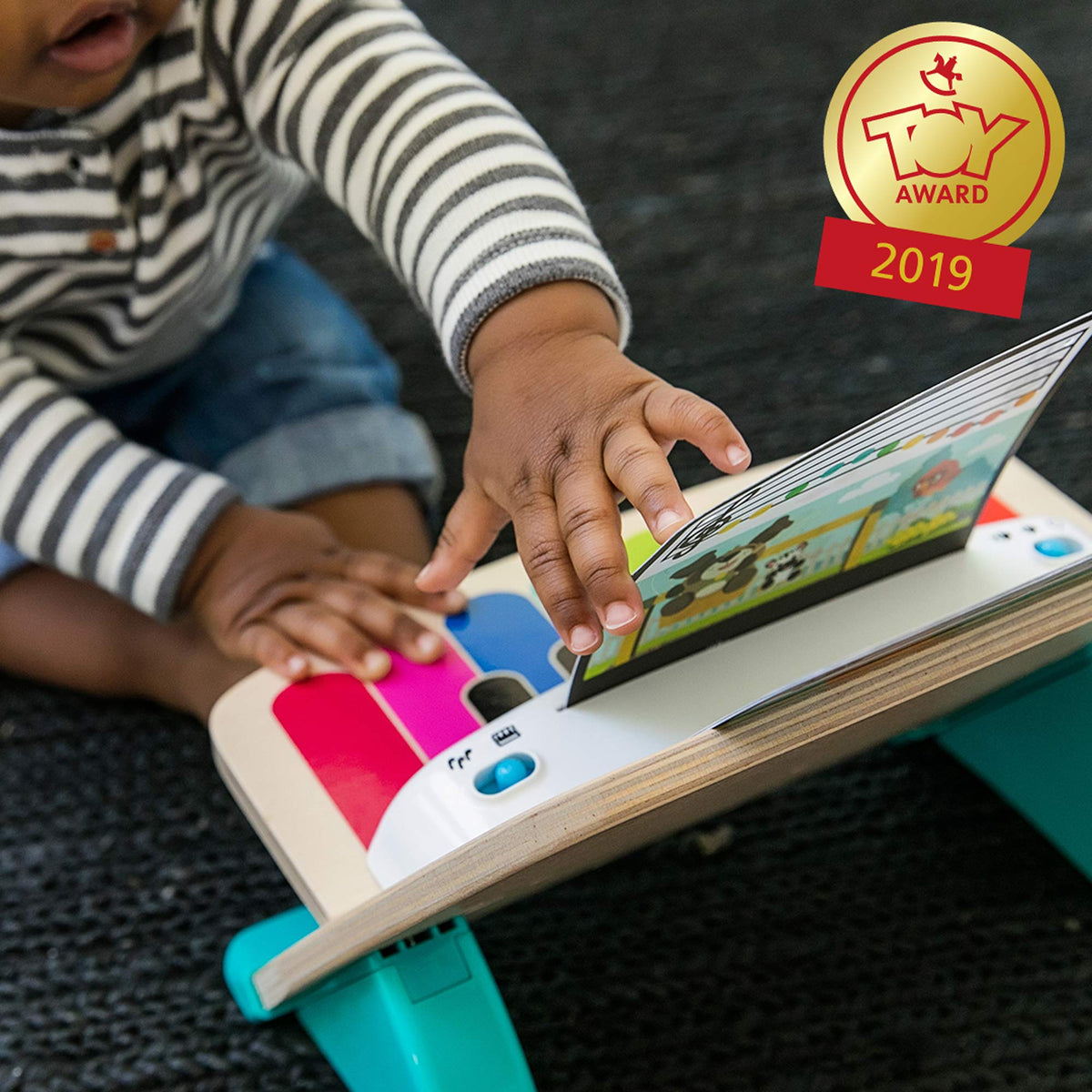 Child hands playing wooden magic piano toy with music screen and colorful keys