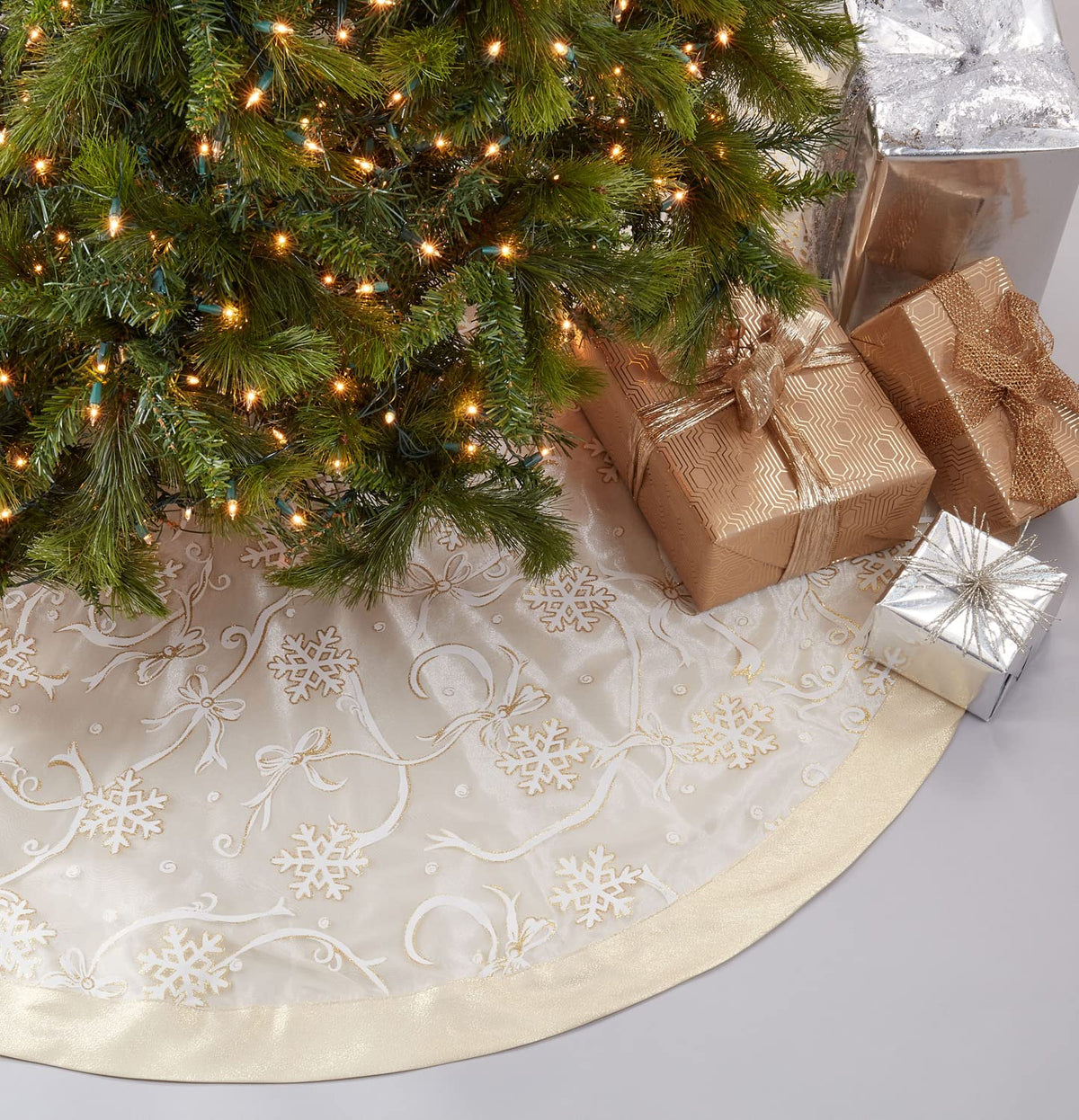 Round Christmas tree skirt in cream with gold-toned snowflake and ribbon print, 52 in.