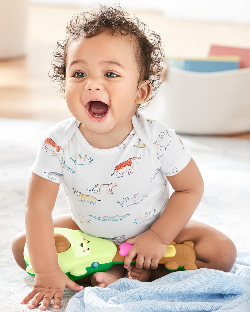 Baby sitting with green avocado guitar toy, pressing colorful light-up buttons