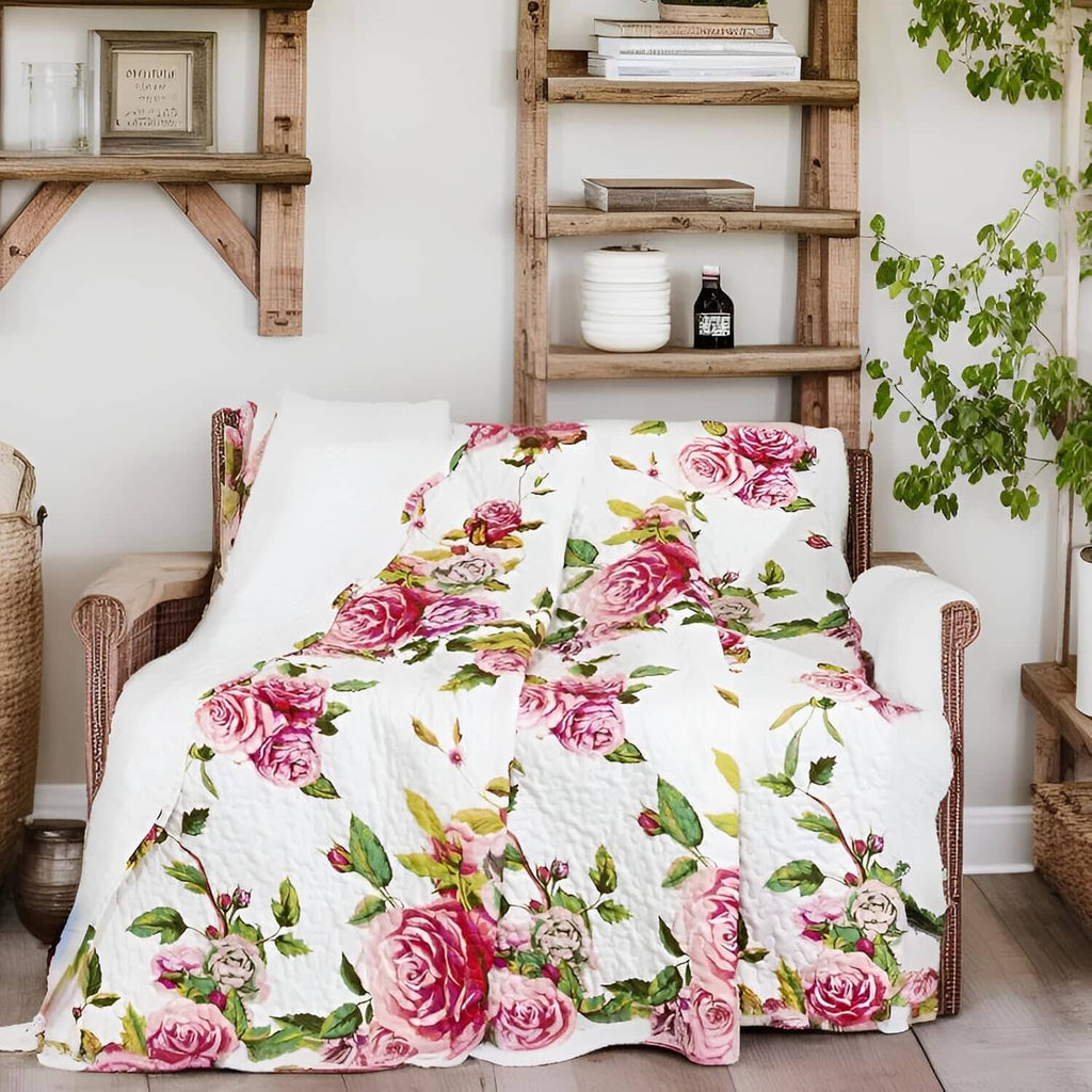 Quilted throw blanket featuring pink roses and green leaves on a white background