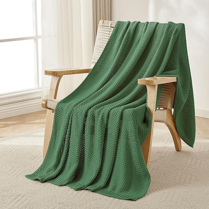 Chunky cable knit cotton throw blanket, olive green, draped over a chair