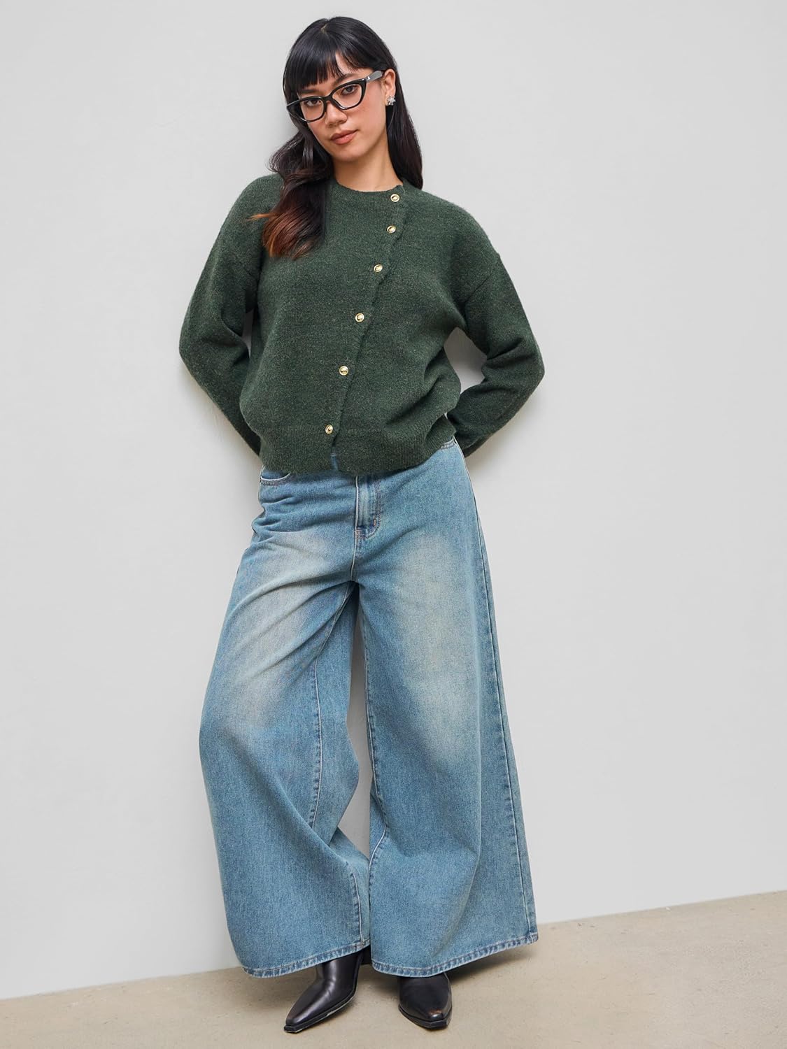 Dark green knit cardigan with long sleeves and gold snap buttons, worn with wide-leg jeans
