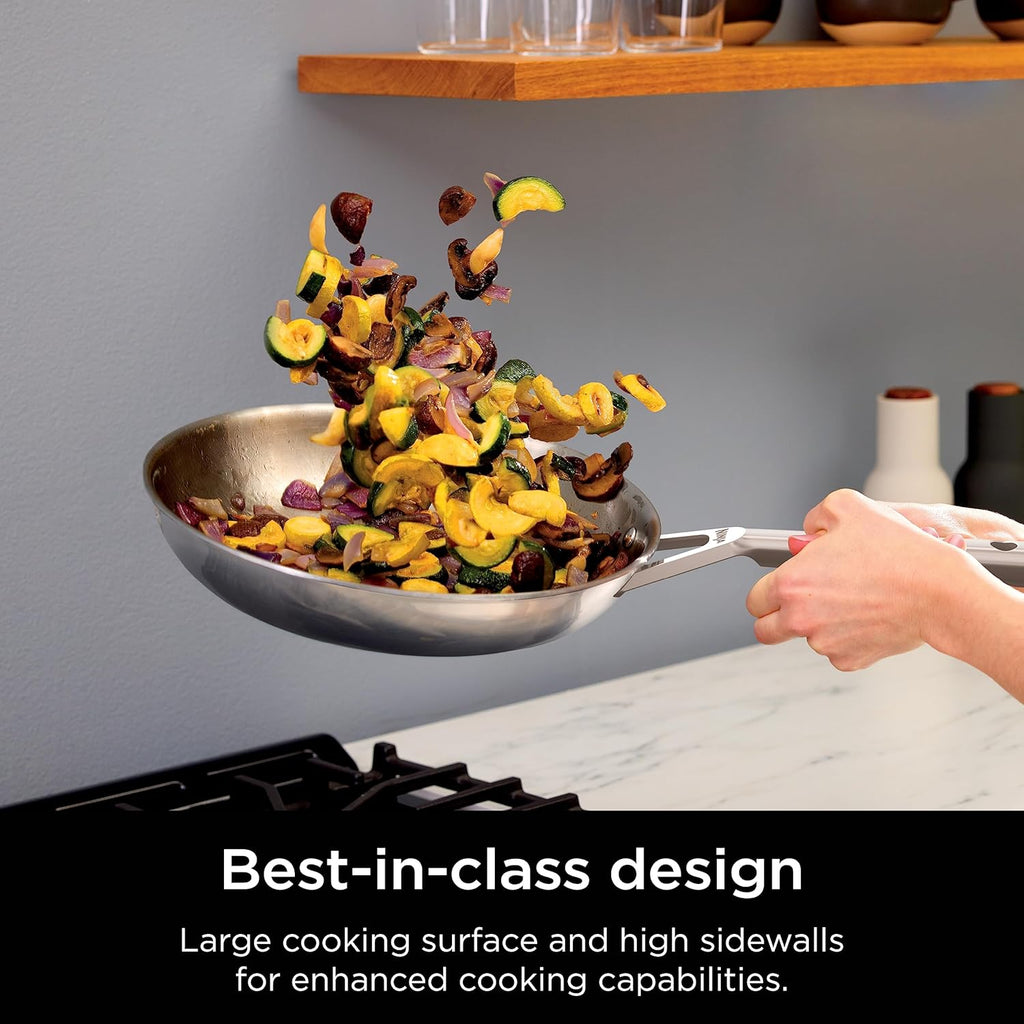 Stainless steel frying pan with vegetables being added by hand