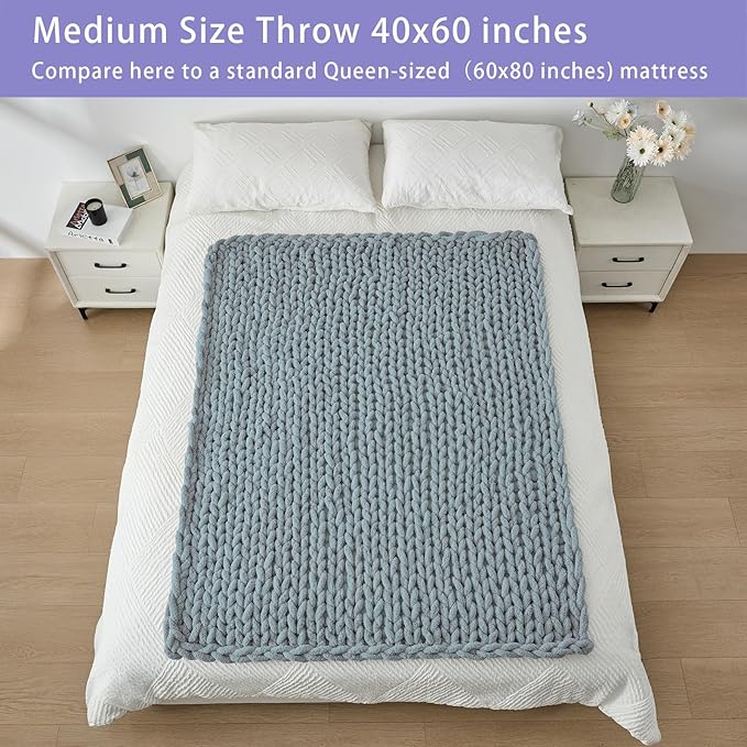 Dusty blue chunky knit throw blanket sized 40 x 60 in on a bed