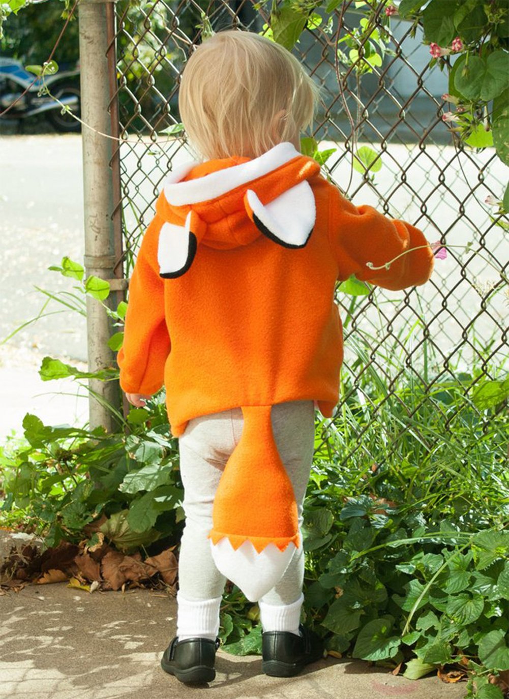Back view of orange animal-ear hoodie with white trim and long sleeves, worn by child outdoors.