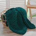 Dark green chunky knit throw blanket with rope-knot cable texture and rounded edges