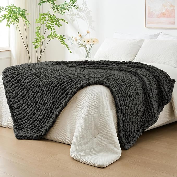 Dark grey chunky knit throw blanket with rope-knot cable texture on a couch