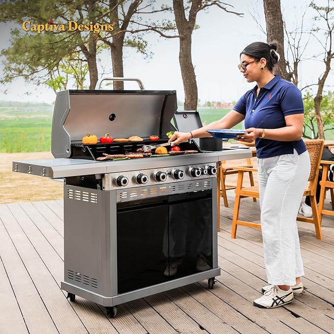 Outdoor BBQ grill with open lid and side burner, person preparing food on deck