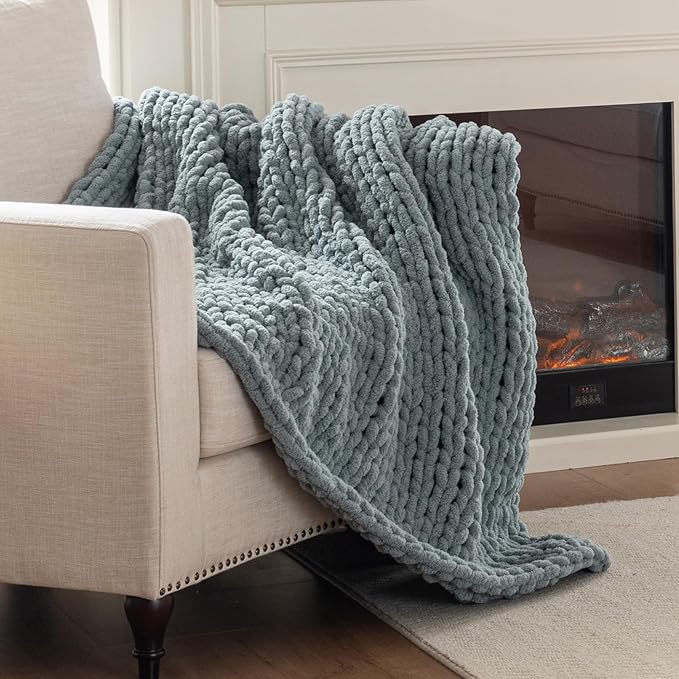 Chunky cable-knit chenille throw blanket in blue, draped over a sofa