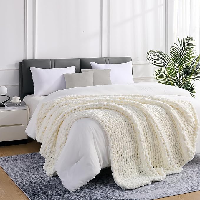 Cream chunky knit blanket throw draped over bed, featuring raised cable stripes