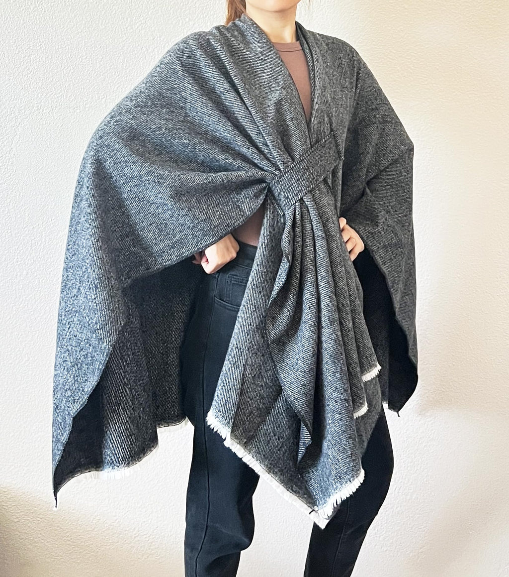 Women’s charcoal-blue fringe poncho shawl with open front and knot at neckline, layered drape.