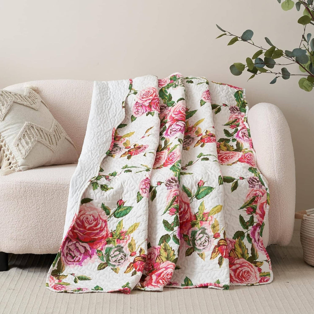 Quilted throw blanket with white base and pink rose floral pattern, scalloped edge look