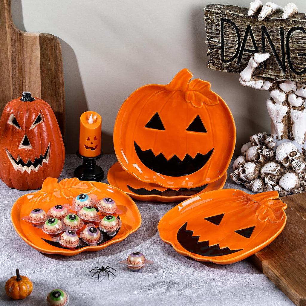 Orange ceramic jack-o'-lantern candy dishes with carved faces on table