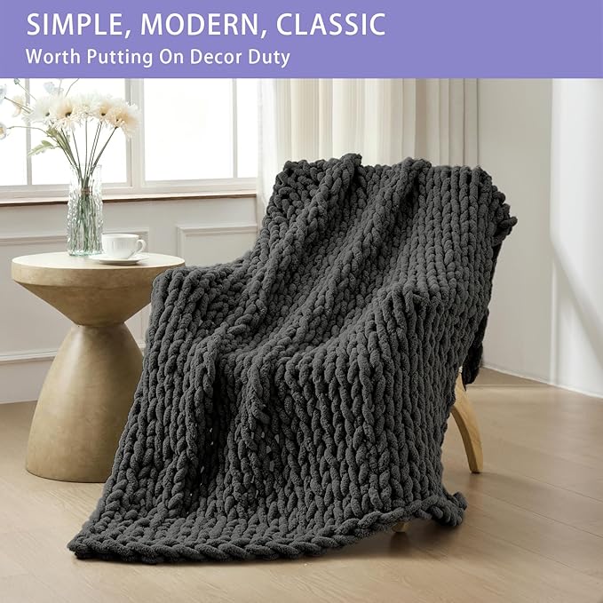 Dark grey chunky chenille throw blanket draped over sofa, rope-knot cable knit design.