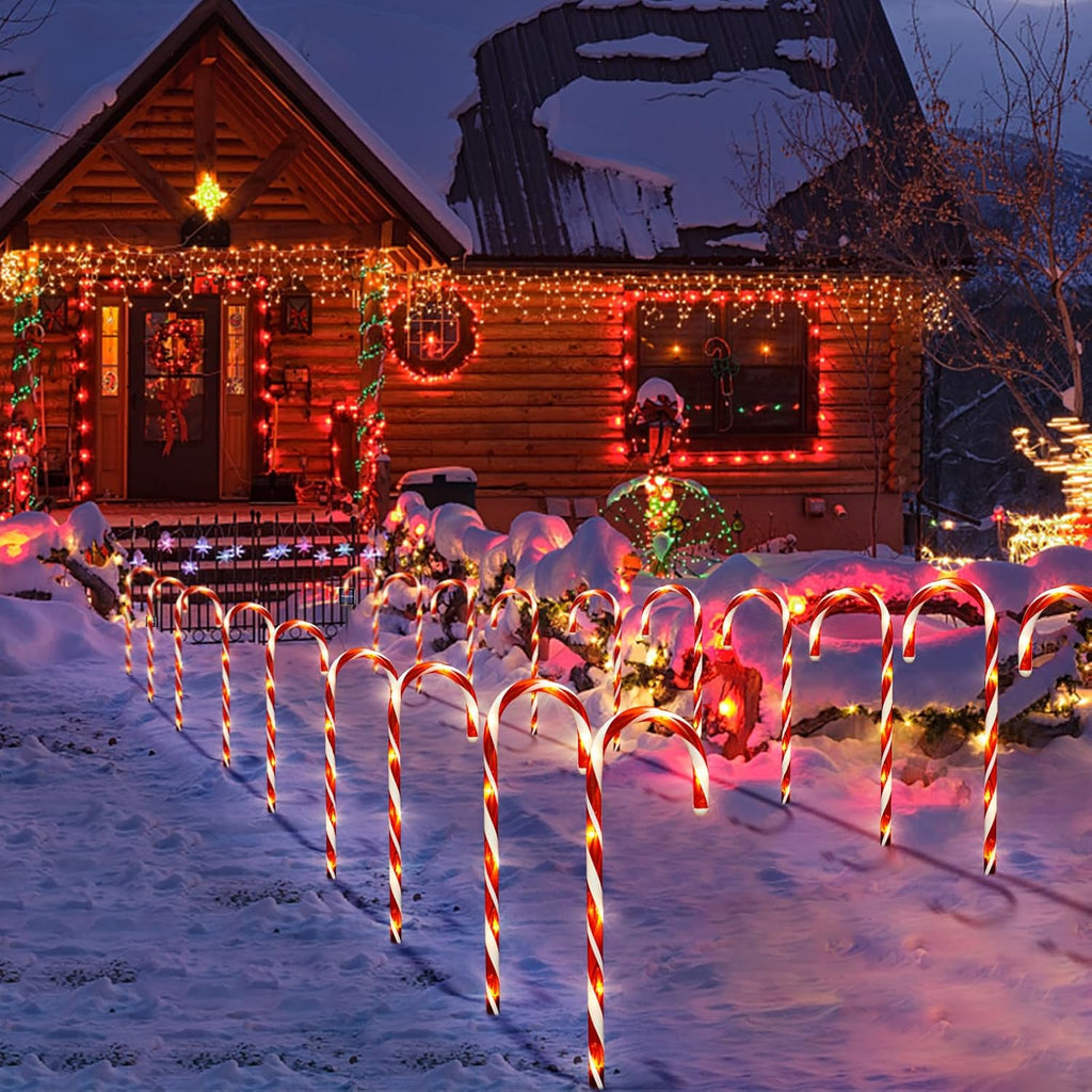 Candy cane solar pathway lights with red and white striped bulbs, glowing in a snowy yard