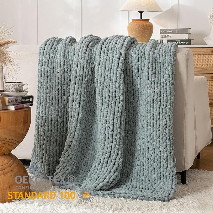 Chunky cable-knit chenille throw blanket in blue, layered on a bed