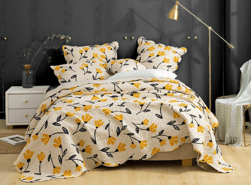 Ivory quilt set with yellow blooms and black leaf pattern, folded bedspread layer