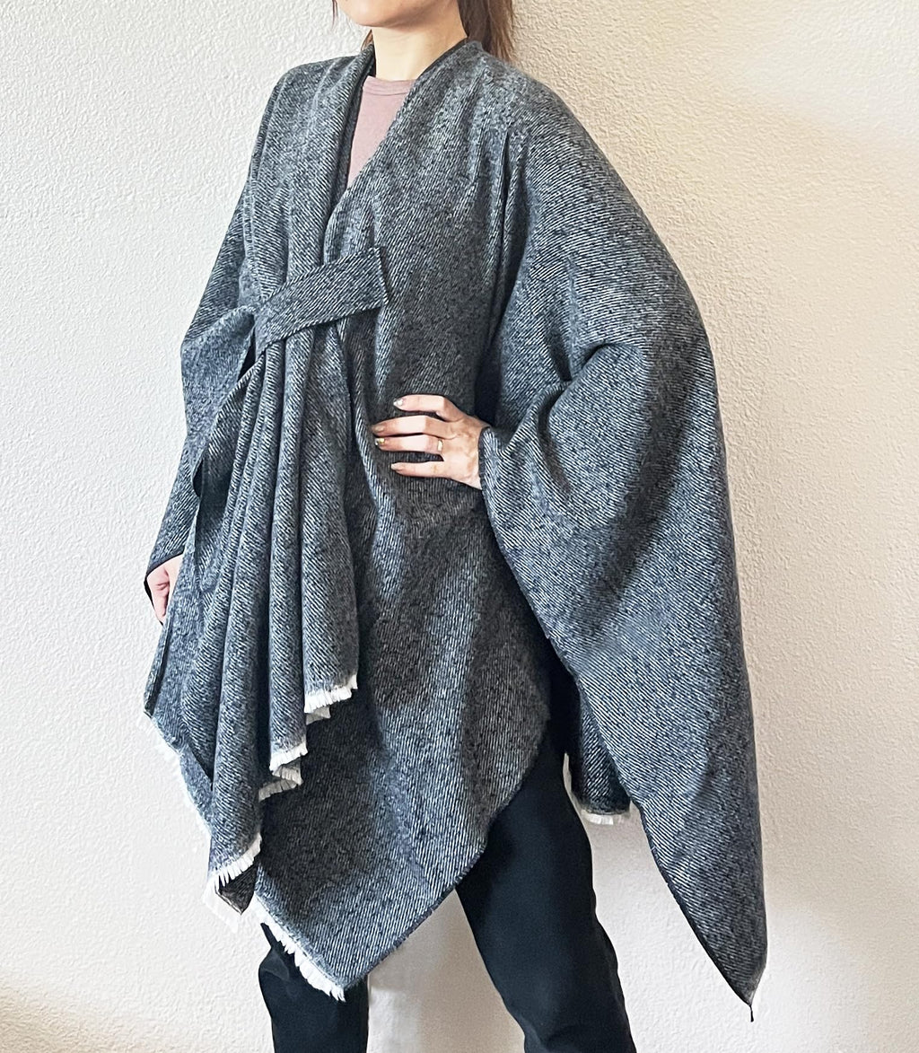 Women’s dark blue-grey fringe poncho shawl with open front and wrap-tie detail, draped cape.