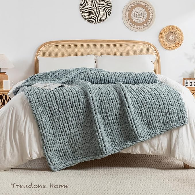 Chunky cable-knit chenille throw blanket in blue folded on a bed