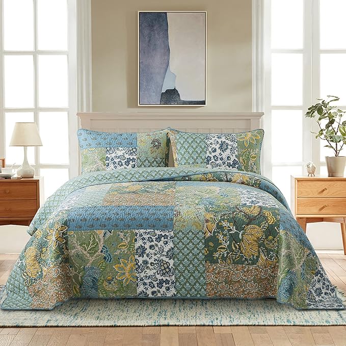 Patchwork quilt bedspread with green, blue, and gold botanical pattern and quilted texture