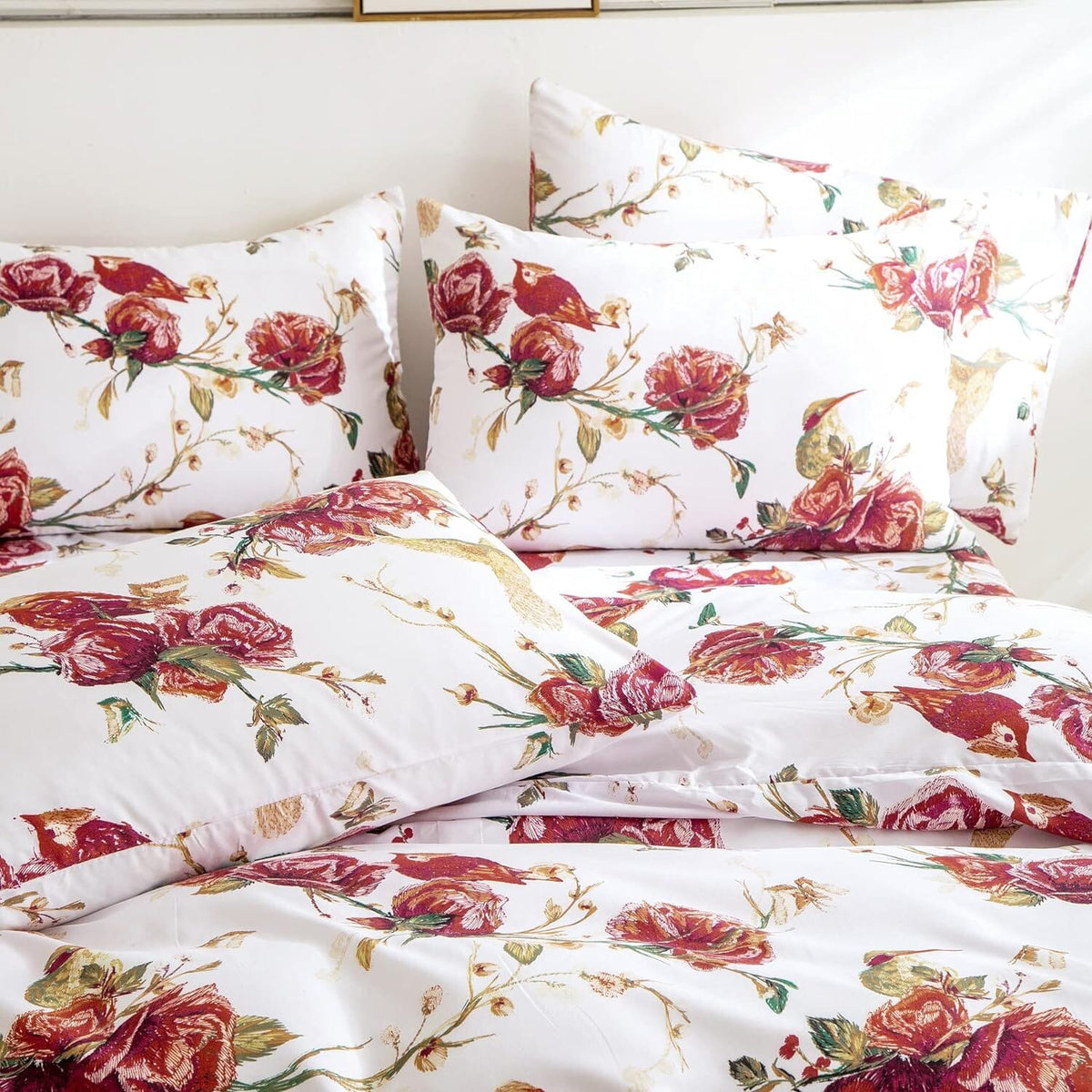 Floral rose and hummingbird pillowcases on bed, white background with burgundy-red blooms.