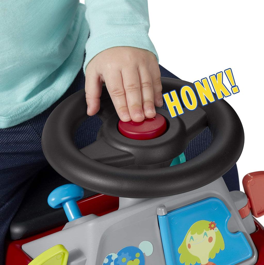 Close-up of toddler hand pressing steering wheel horn on red ride-on car