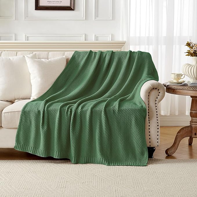 Chunky cable knit cotton throw blanket, olive green, folded on a sofa