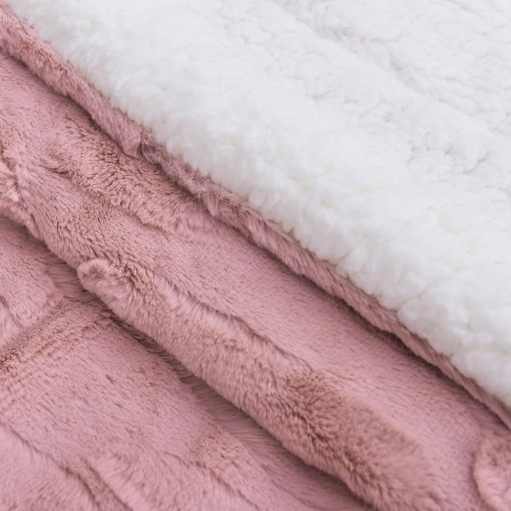 Close-up of dusty pink faux fur blanket with white underside edge and seam