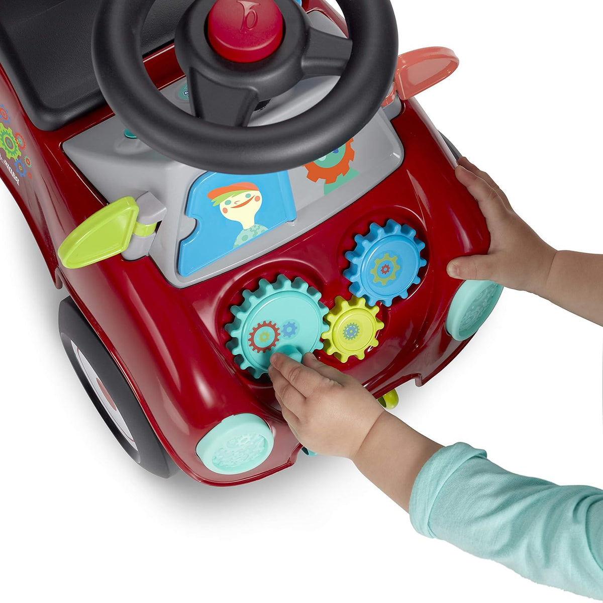 Red ride-on car front with steering wheel and hand-turned gear toys on dashboard.