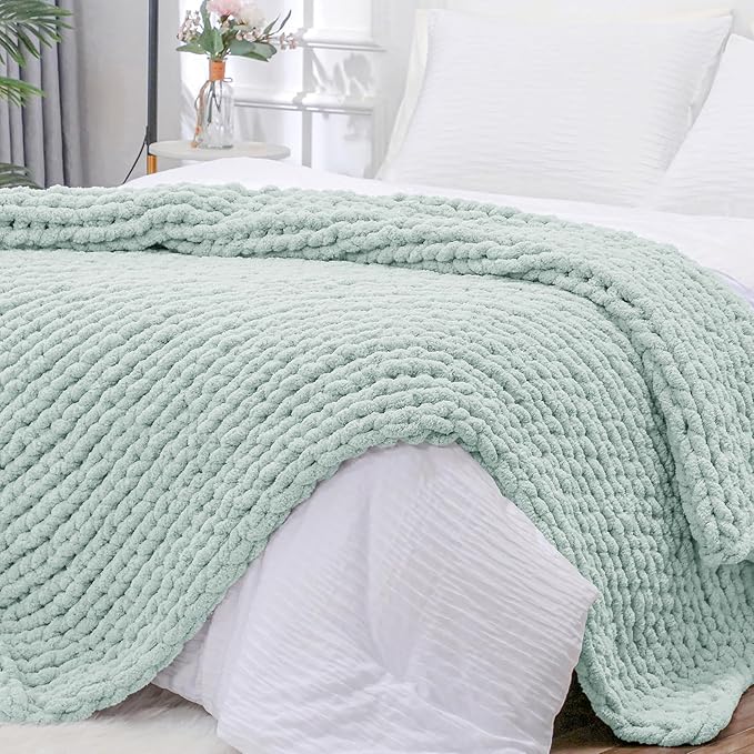 Mint chunky knit throw blanket with rope-cable cable stitch draped over bed pillows