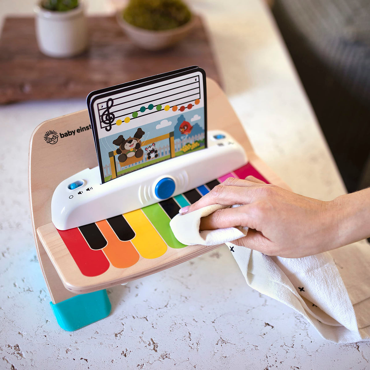 Hand playing wooden magic touch piano toy with colorful keys and screen display