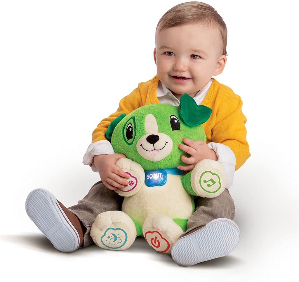 Plush green song-learning bear toy being held by a smiling baby