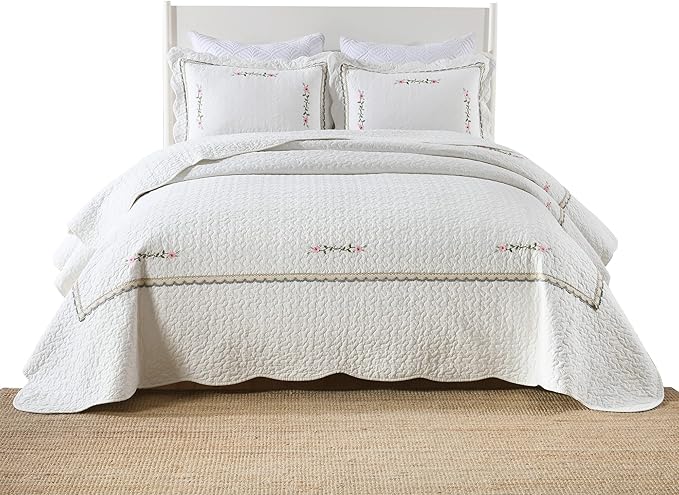 White oversized quilt with embroidered floral sprigs and curved stitched border
