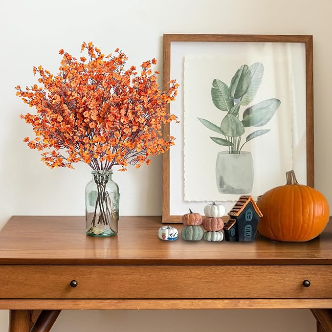Orange artificial baby's breath bouquet with glass vase on tabletop