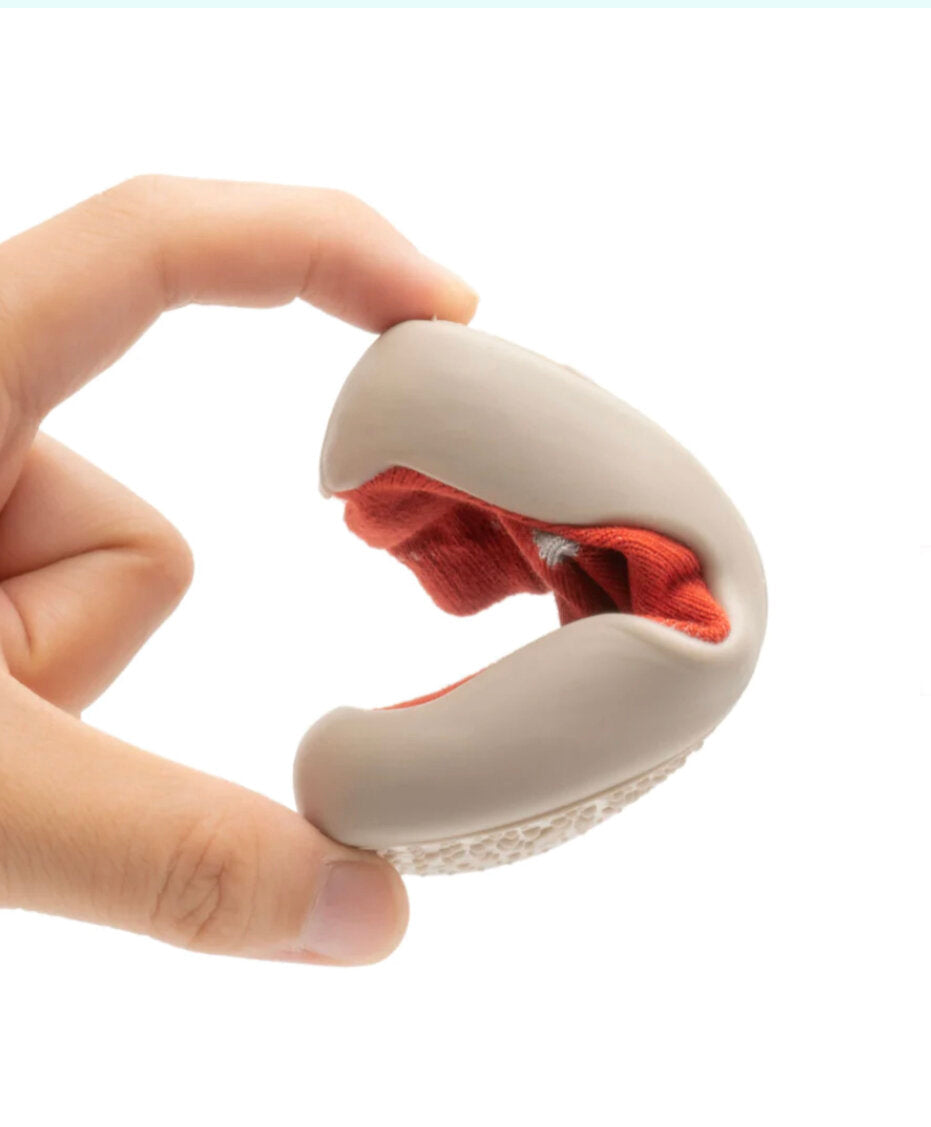 Red knitted barefoot sock shoe with white sole, shown held open by fingers.