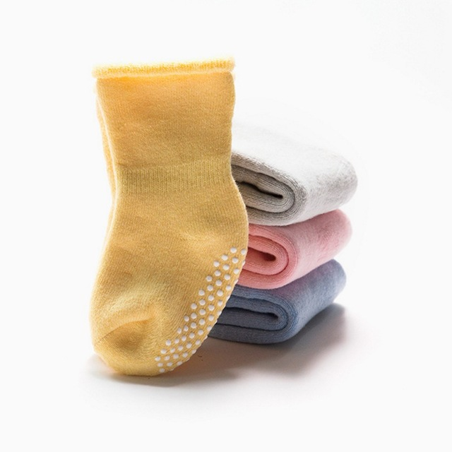 Yellow and grey children non-slip socks stacked, with dotted grip on foot