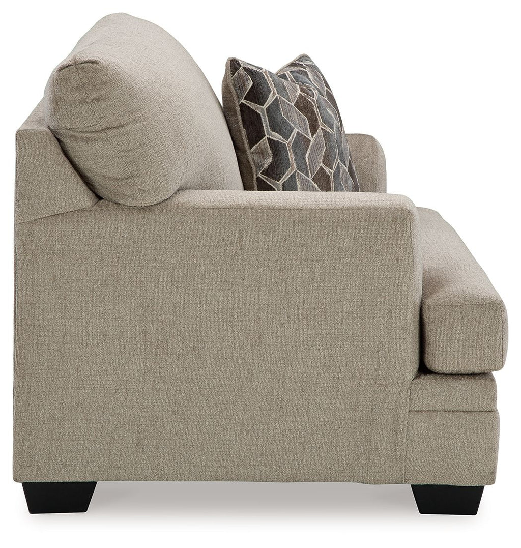 Upholstered sofa chair with rounded arm, light gray-brown fabric and decorative throw pillows