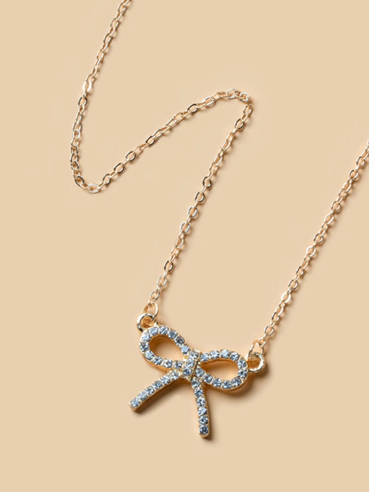Gold knot pendant necklace with blue rhinestone ribbon bow and layered chain
