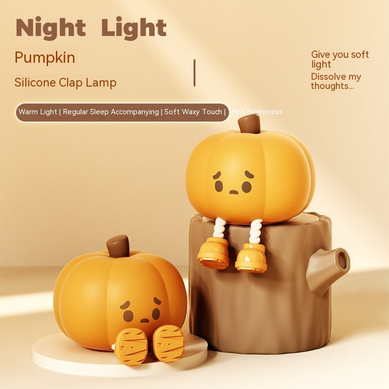 Silicone clap pumpkin night light with sad face, warm glow on tabletop