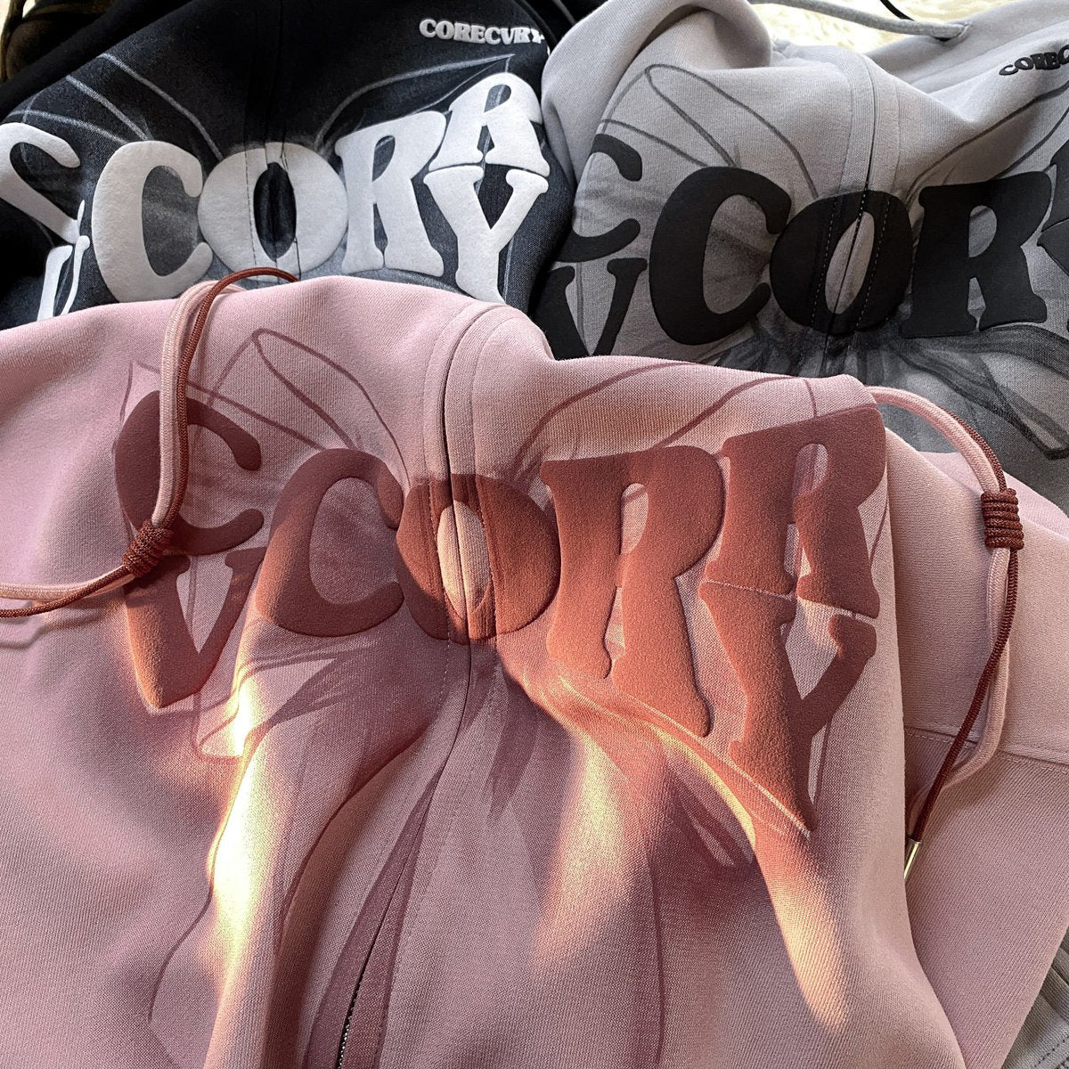 Pink hoodie close-up with foamed front graphic, drawstring and zipper
