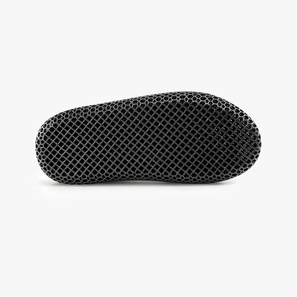 Black 3D-printed mesh slipper, side view with closed back and contoured sole.