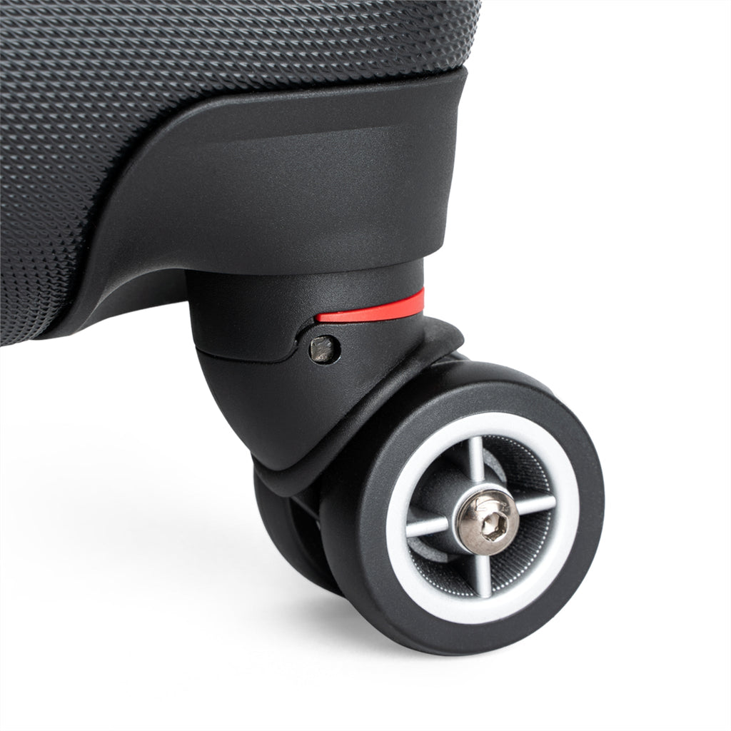 Hard-shell suitcase wheel close-up with silver axle and red accent, black finish